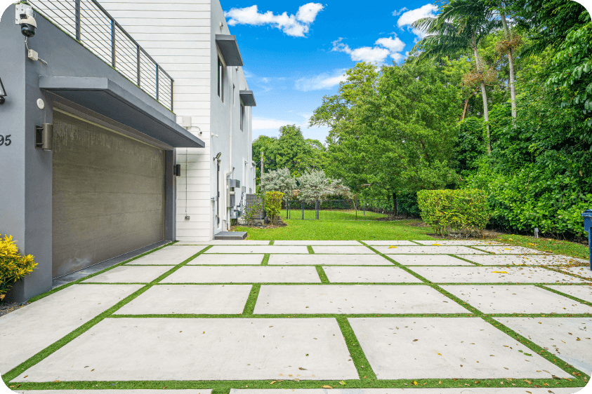 Contemporary garage facade with open driveway, tropical landscaping, and white modern architecture in Pinecrest luxury property