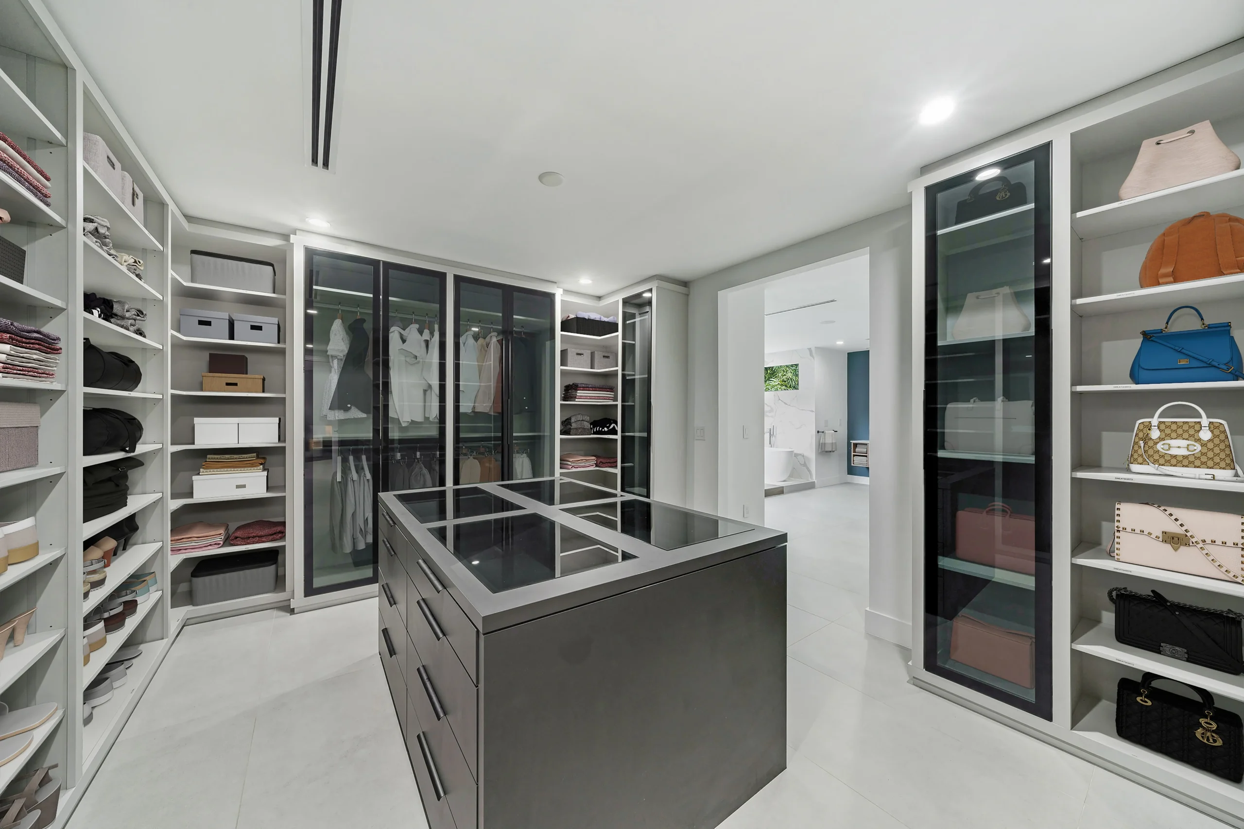 Luxury walk-in closet with custom cabinetry and handbag display in Pinecrest estate